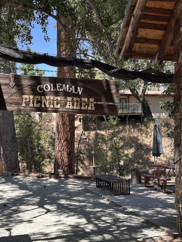 Coleman picnic area sign with picnic tables and umbrellas